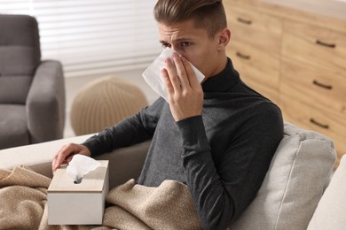 Young man with tissue suffering from sinusitis at home