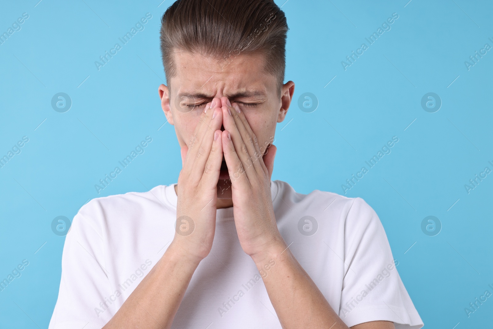 Photo of Young man suffering from sinusitis on light blue background