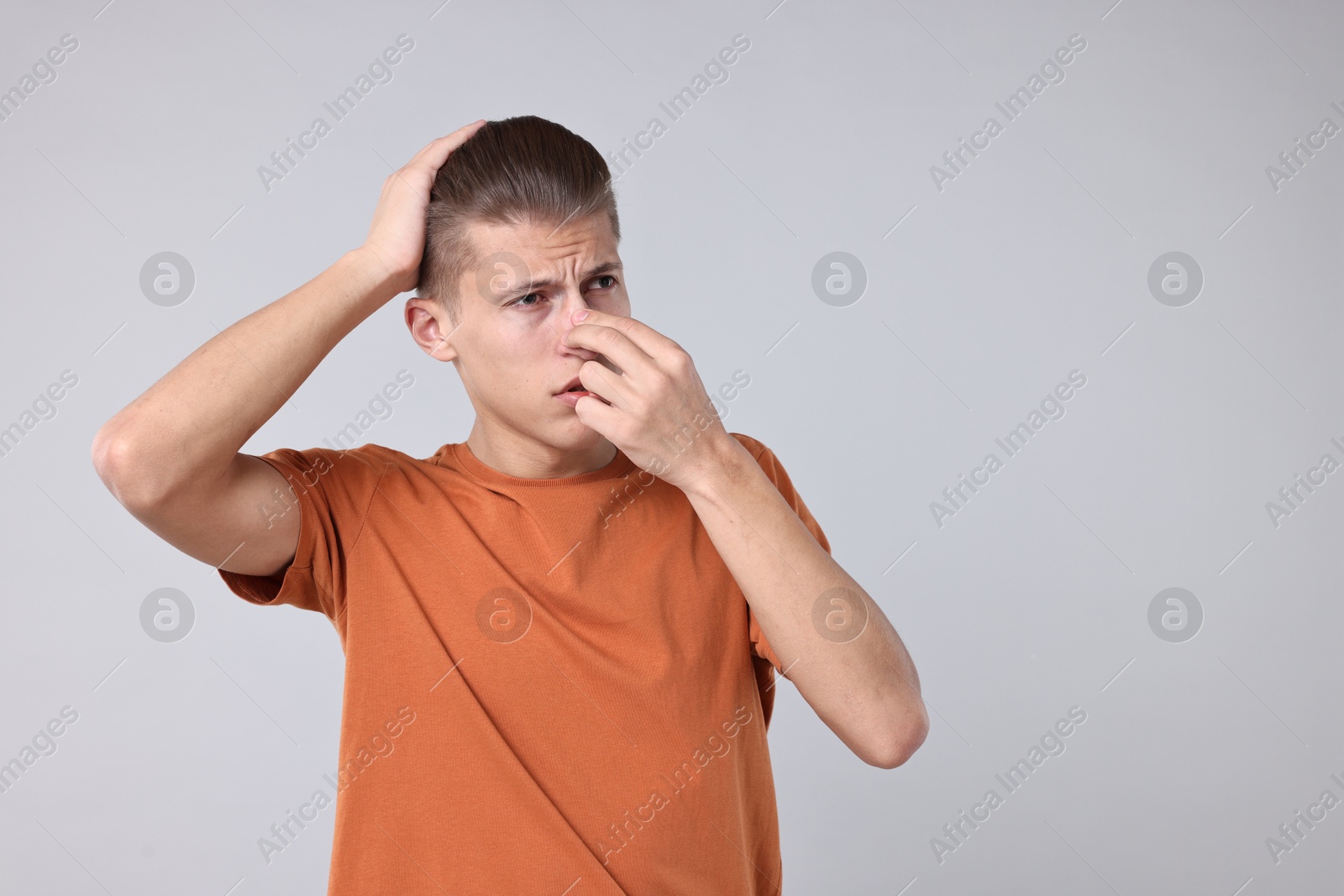 Photo of Young man suffering from sinusitis on light grey background, space for text