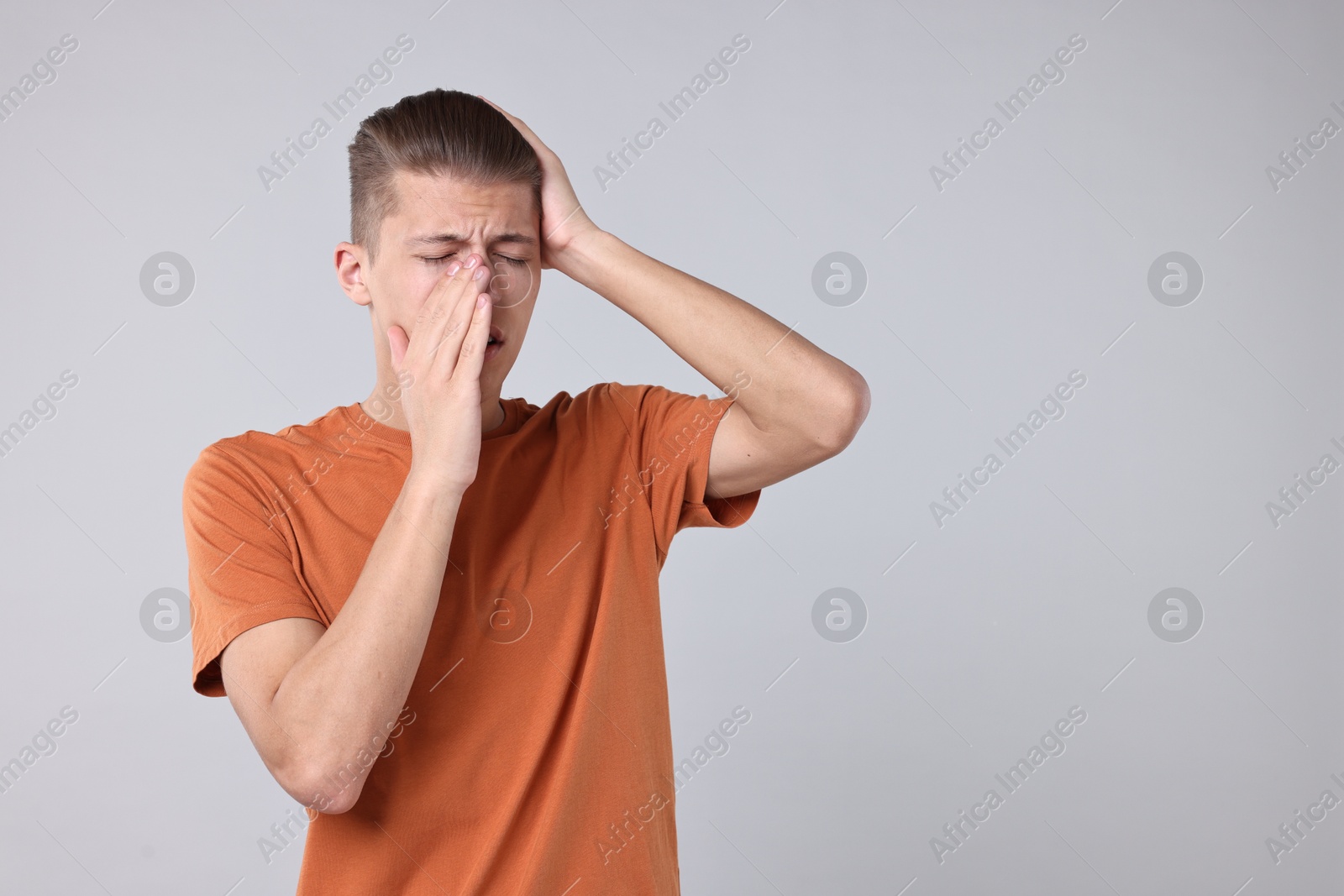 Photo of Young man suffering from sinusitis on light grey background, space for text