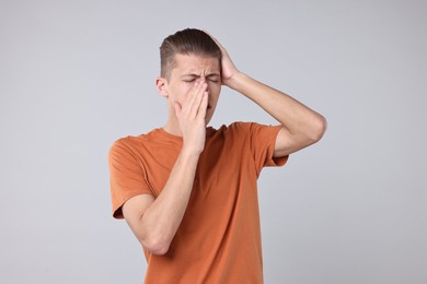 Photo of Young man suffering from sinusitis on light grey background