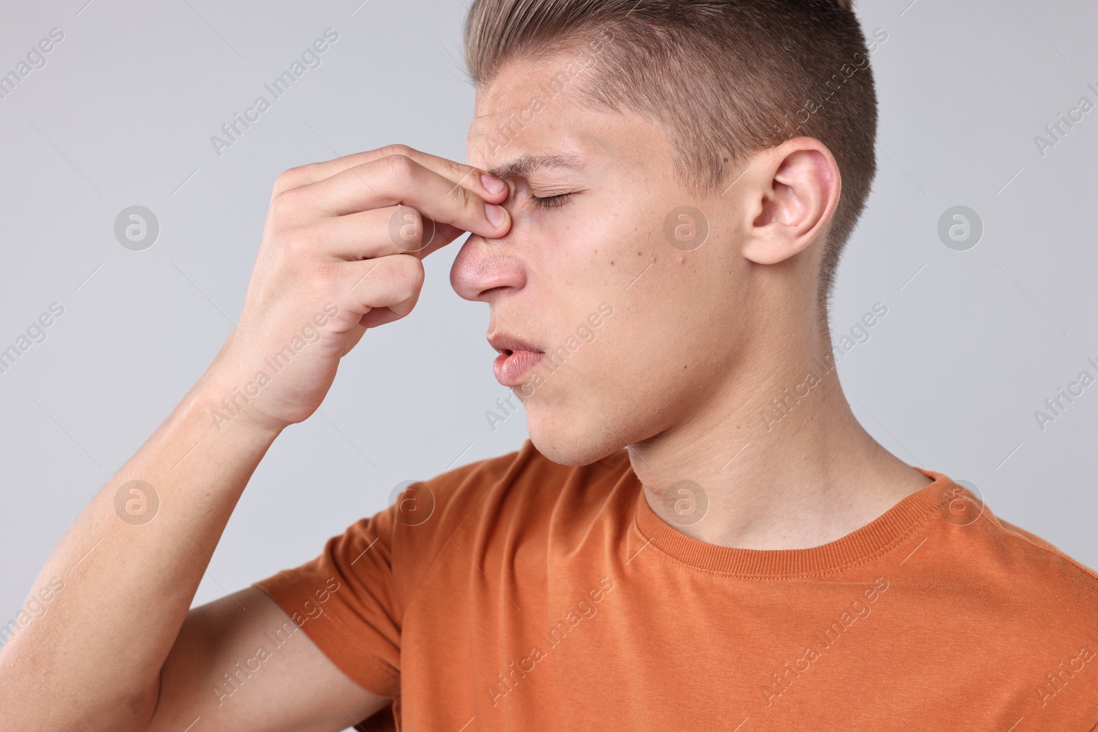 Photo of Young man suffering from sinusitis on light grey background