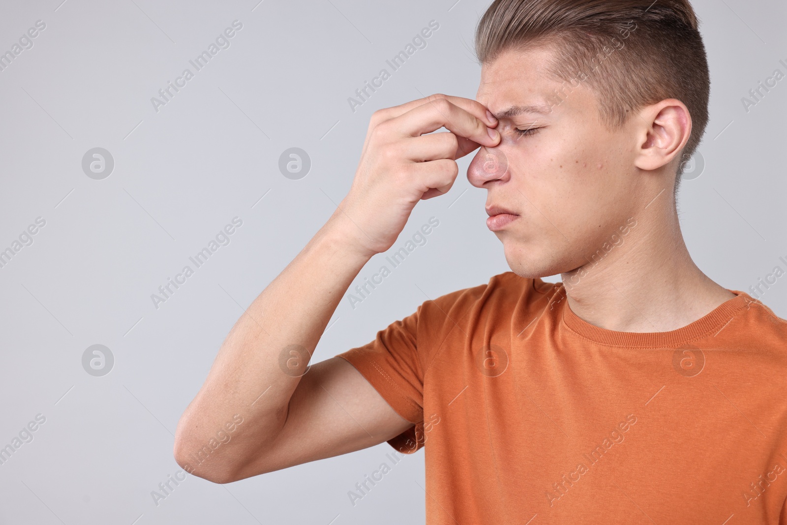 Photo of Young man suffering from sinusitis on light grey background, space for text