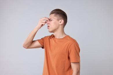 Photo of Young man suffering from sinusitis on light grey background