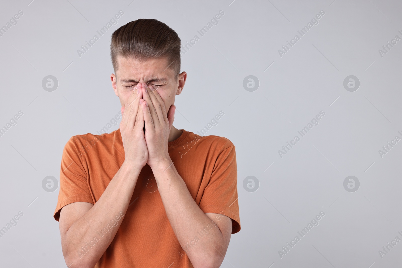 Photo of Young man suffering from sinusitis on light grey background, space for text