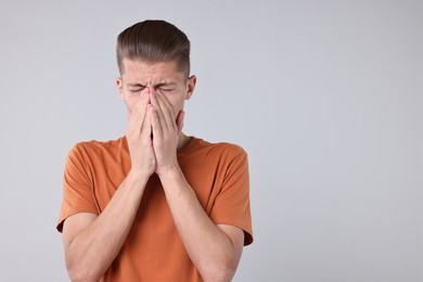 Young man suffering from sinusitis on light grey background, space for text