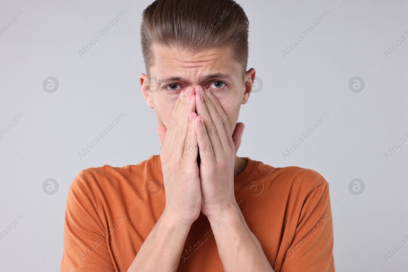 Photo of Young man suffering from sinusitis on light grey background