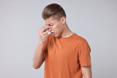 Photo of Young man suffering from sinusitis on light grey background