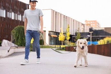 Happy owner walking with cute Golden Retriever dog outdoors