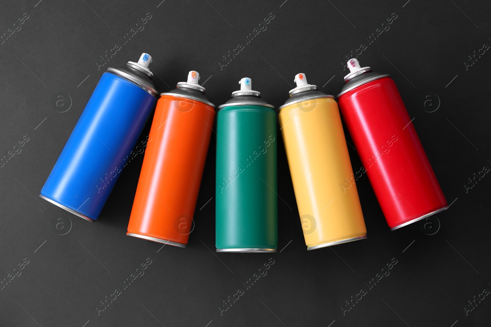 Photo of Many spray paint cans on dark gray background, top view