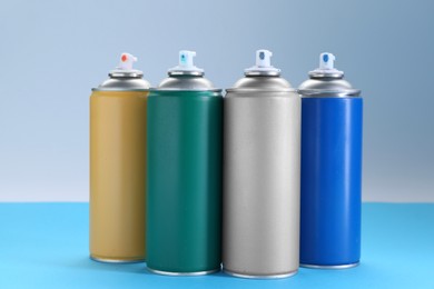 Photo of Many spray paint cans on color background