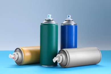 Photo of Many spray paint cans on color background