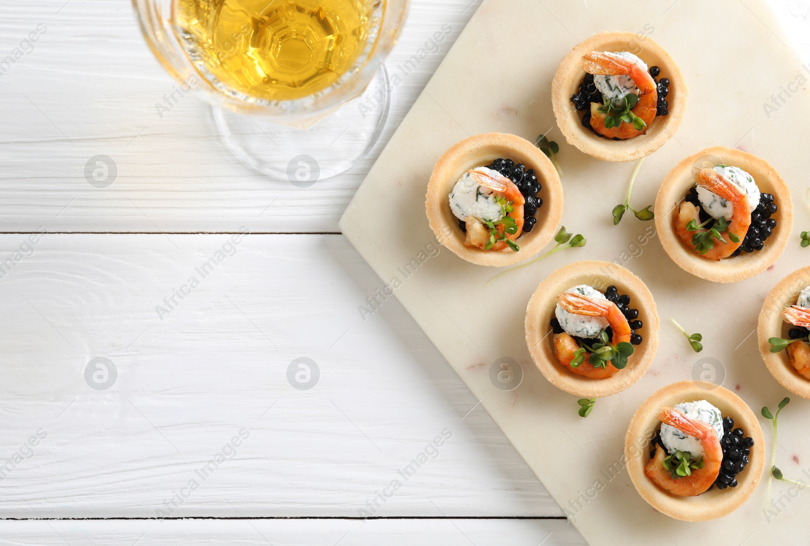 Photo of Delicious canapes with shrimps and glass of wine on white wooden table, flat lay. Space for text