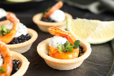 Delicious canapes with shrimps and black caviar on table, closeup