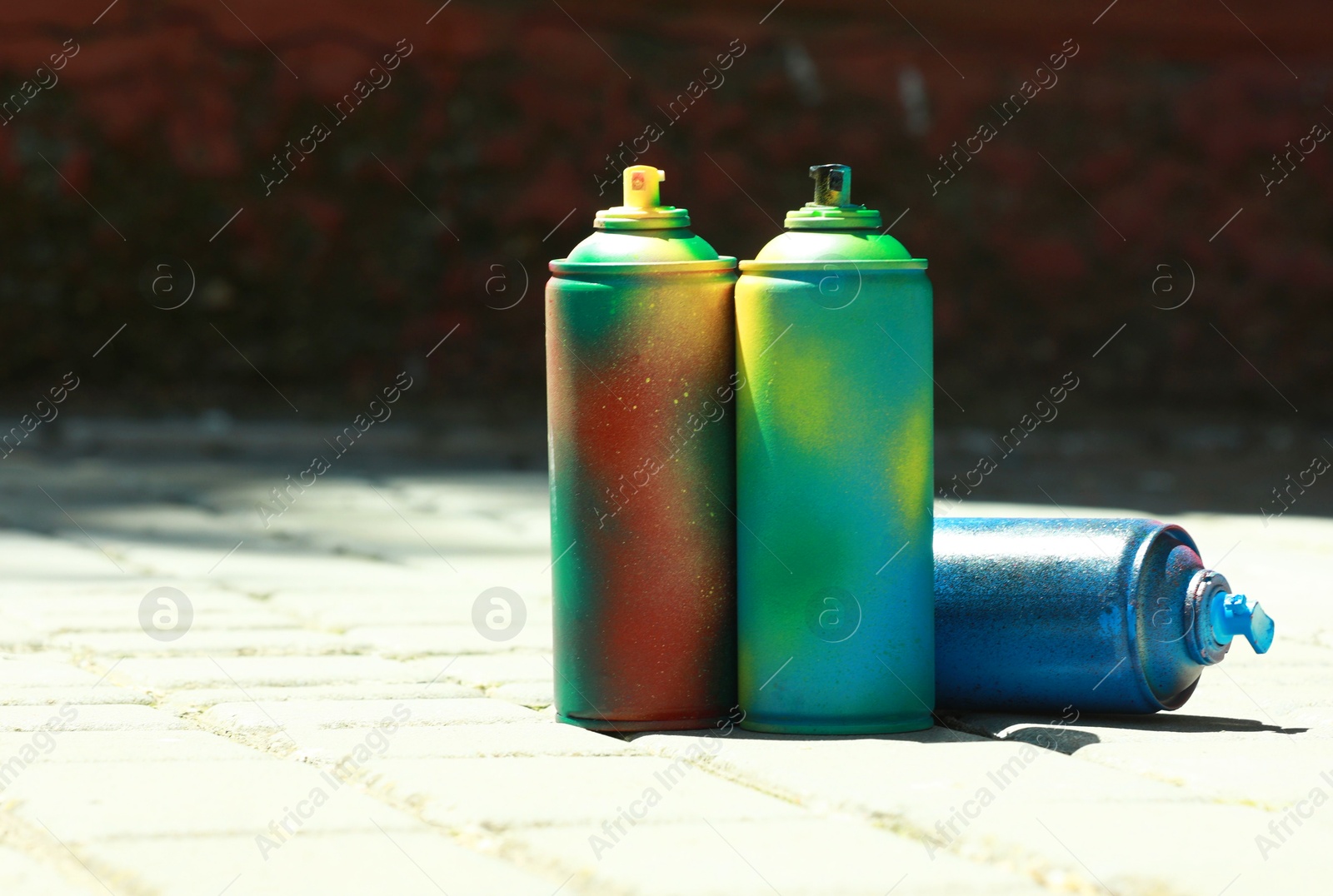 Photo of Many spray paint cans outdoors on sunny day, space for text