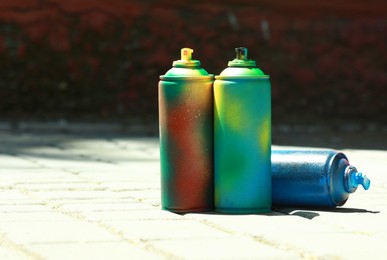 Photo of Many spray paint cans outdoors on sunny day, space for text