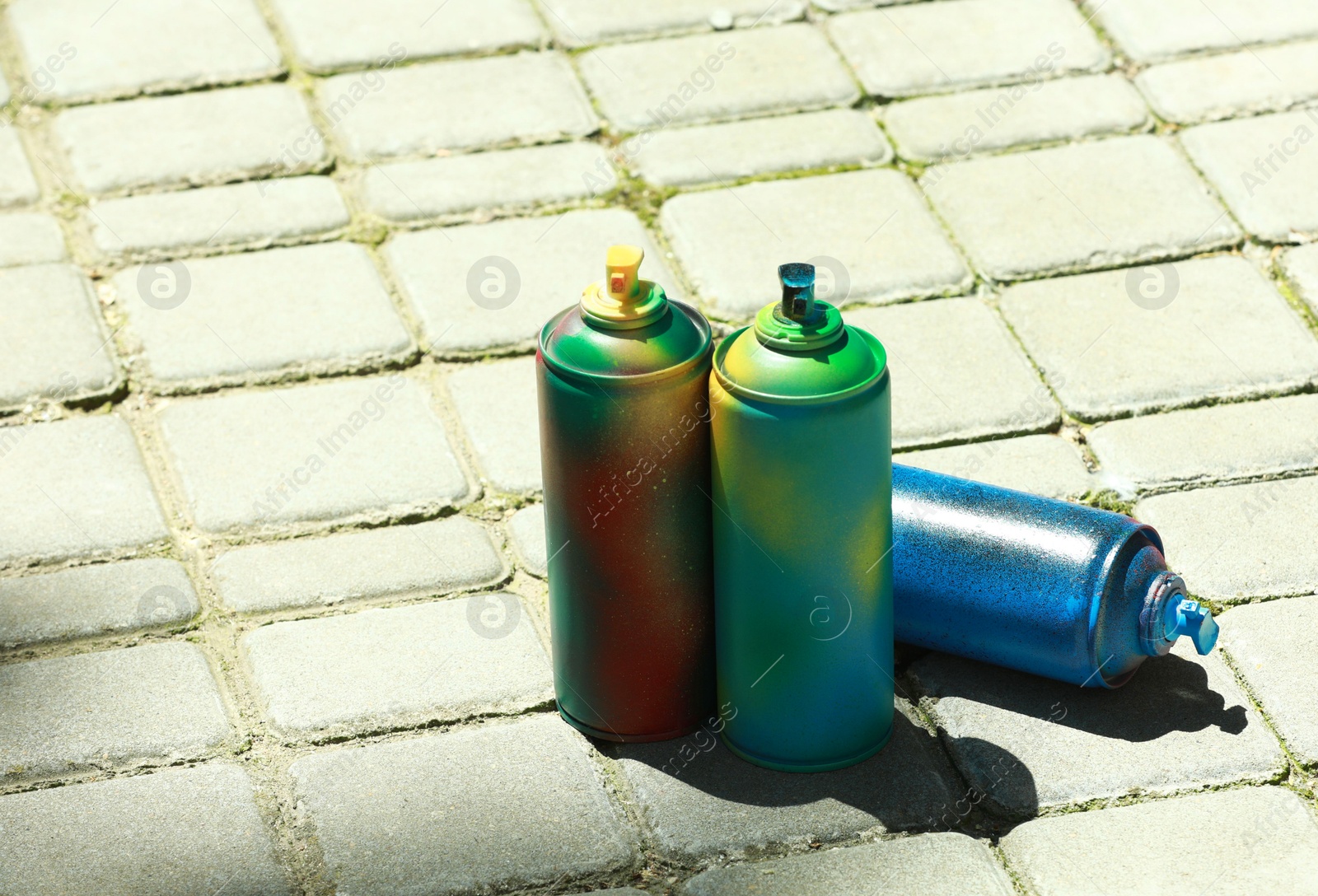 Photo of Many spray paint cans outdoors on sunny day, space for text