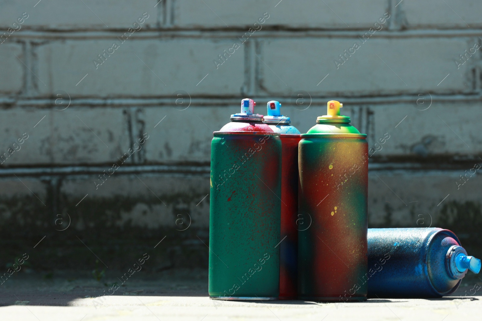 Photo of Many spray paint cans outdoors on sunny day, space for text