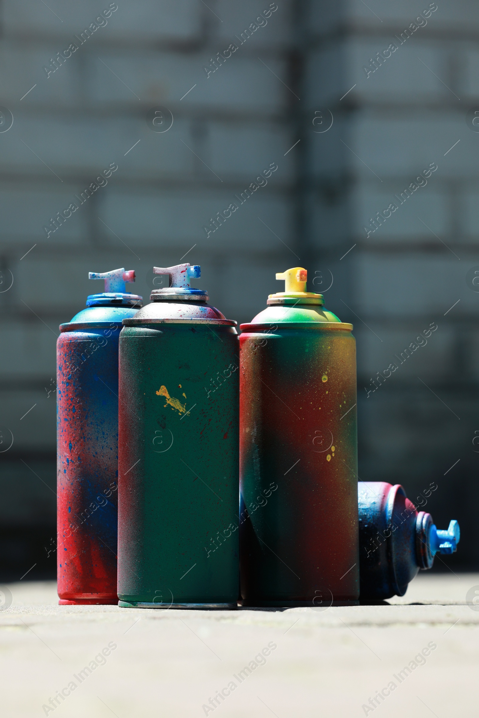 Photo of Many spray paint cans outdoors on sunny day