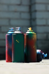 Photo of Many spray paint cans outdoors on sunny day