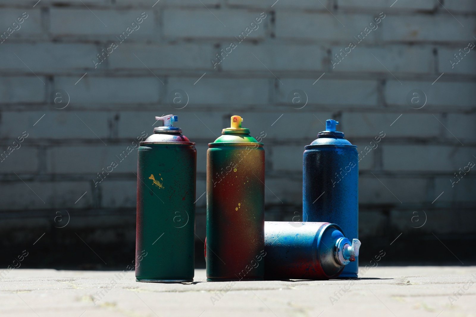 Photo of Many spray paint cans outdoors on sunny day