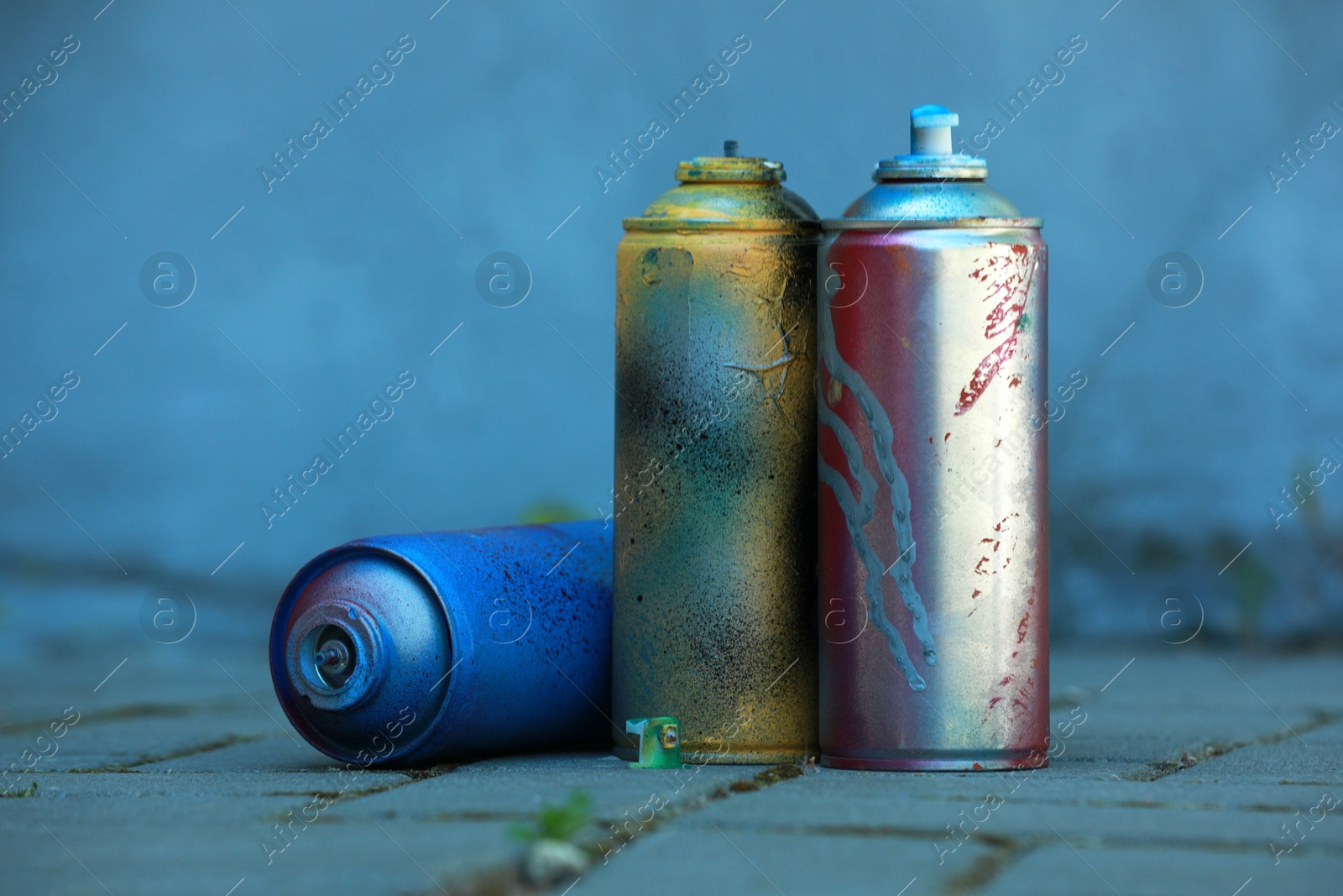 Photo of Many spray paint cans on pavement outdoors