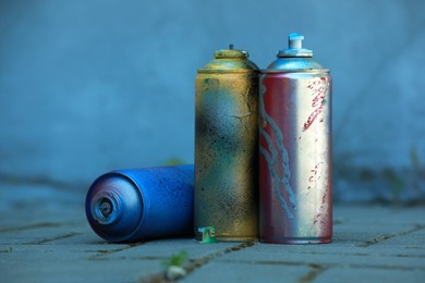 Many spray paint cans on pavement outdoors