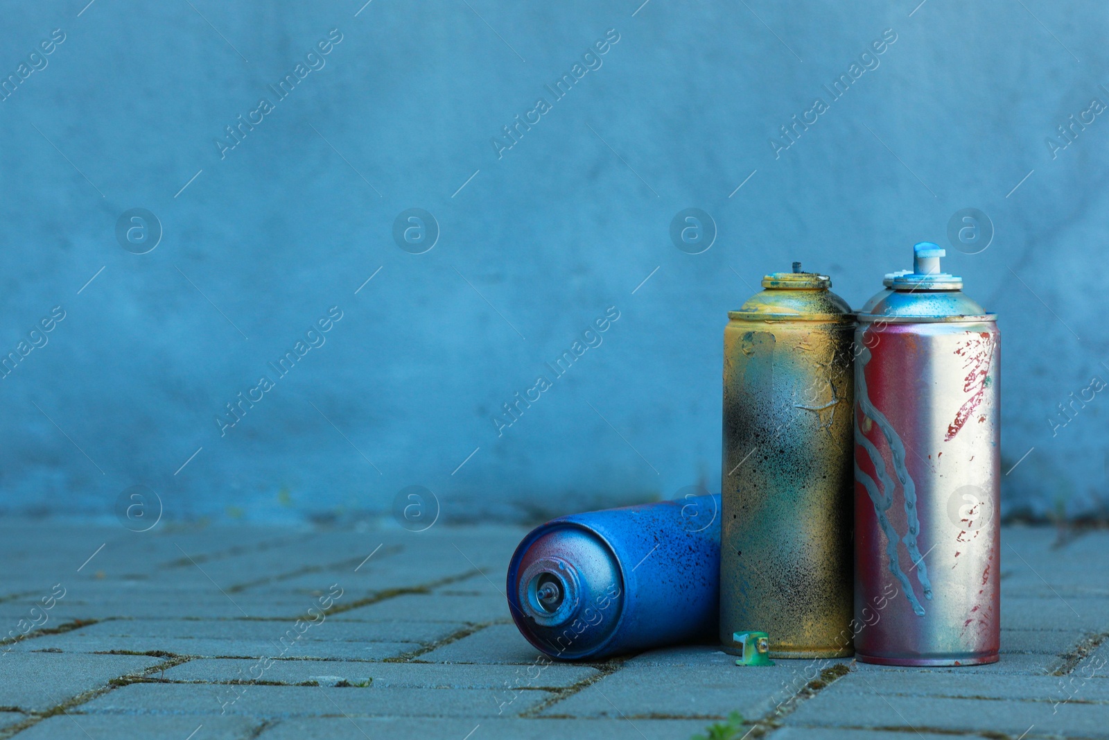 Photo of Many spray paint cans on pavement outdoors, space for text