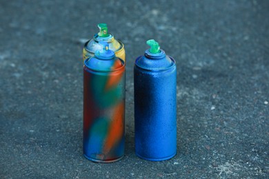 Many spray paint cans on ground outdoors