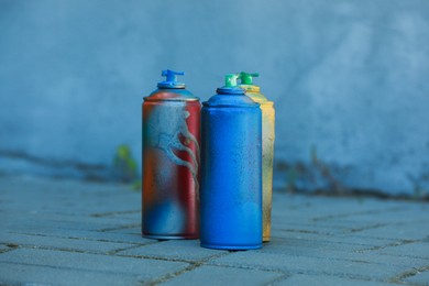 Many spray paint cans on pavement outdoors