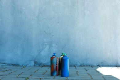 Photo of Many spray paint cans outdoors, space for text