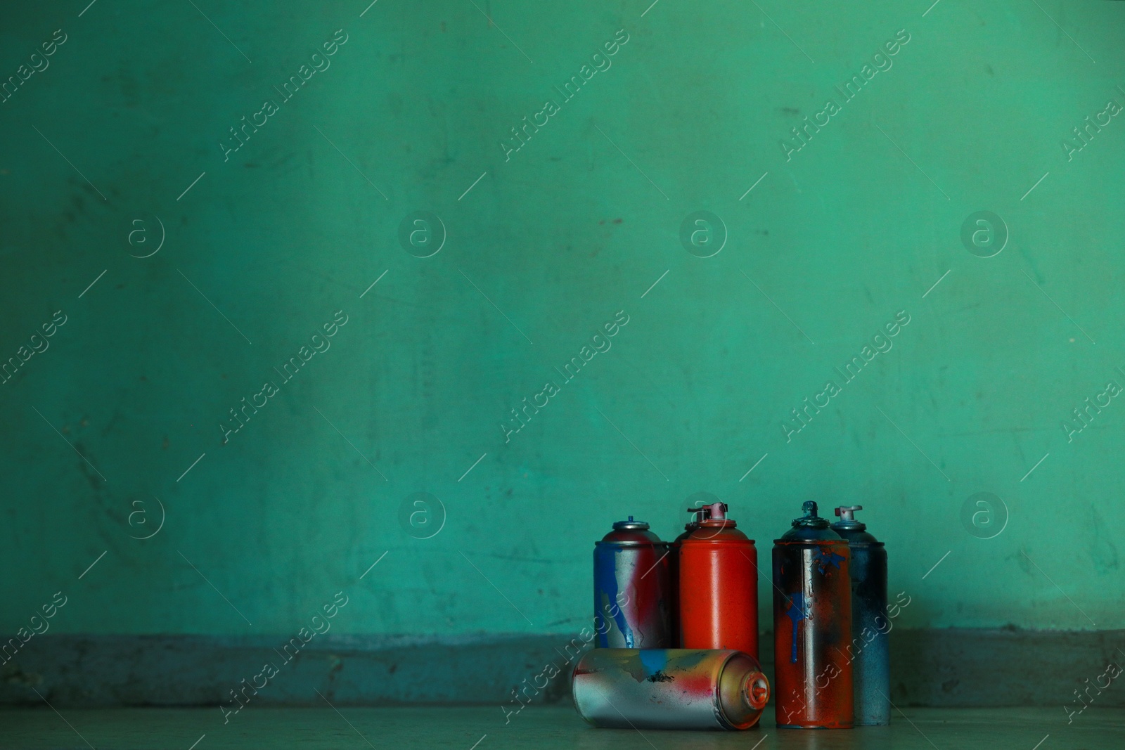 Photo of Many spray paint cans near green wall, space for text