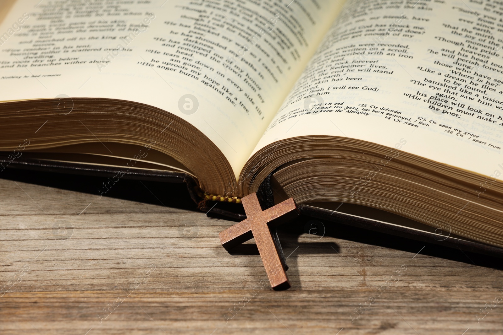 Photo of Bible and cross on wooden table, closeup. Religion of Christianity