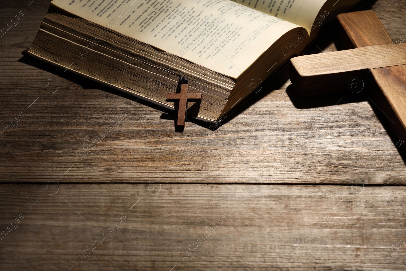 Photo of Bible and crosses on wooden table, space for text. Religion of Christianity