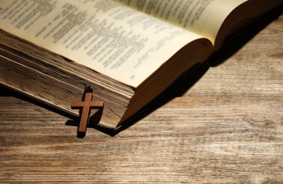 Photo of Bible and cross on wooden table, space for text. Religion of Christianity