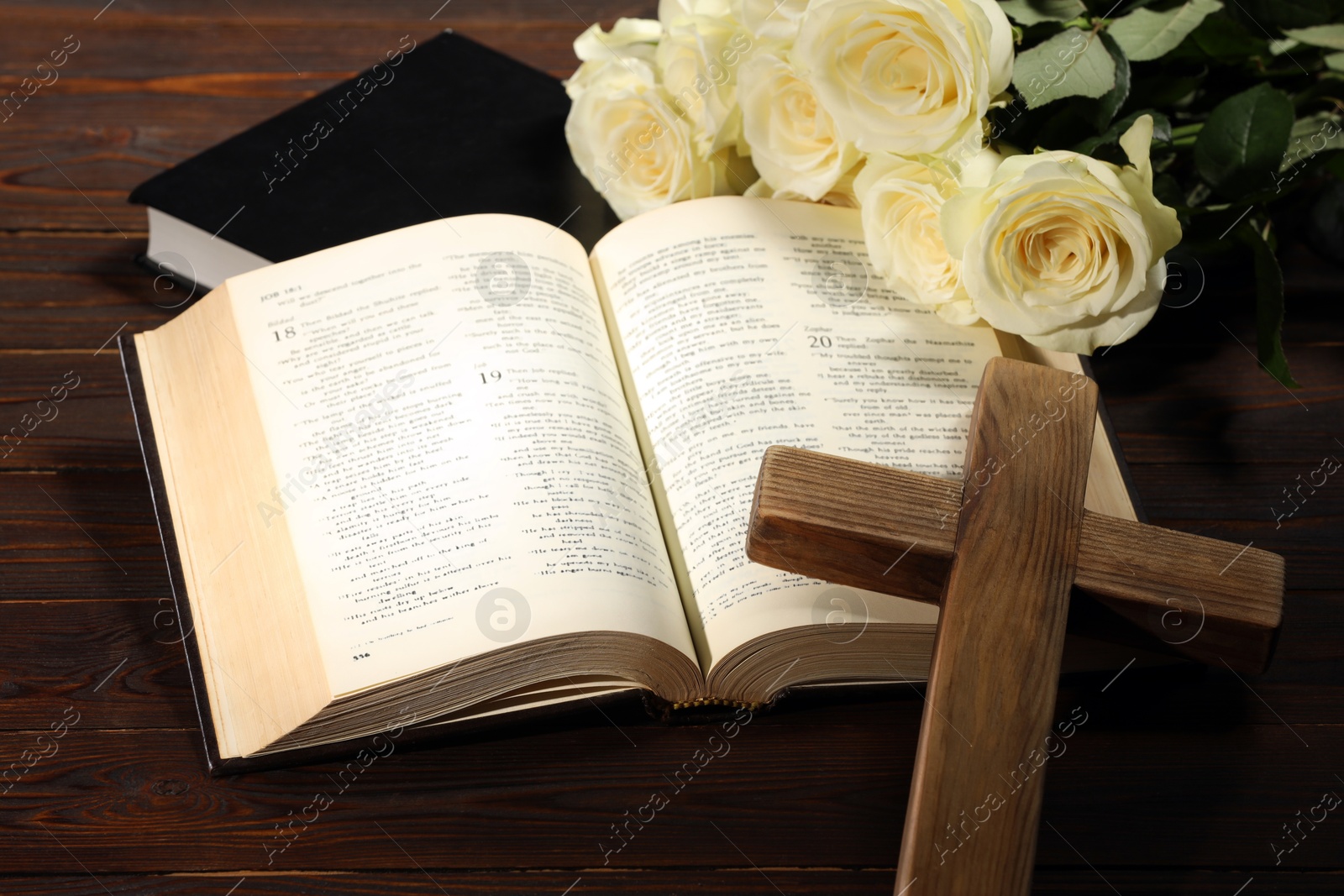 Photo of Bibles, cross and roses on wooden table, closeup. Religion of Christianity