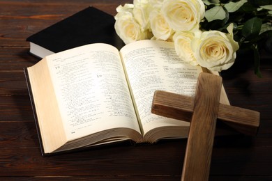 Bibles, cross and roses on wooden table, closeup. Religion of Christianity