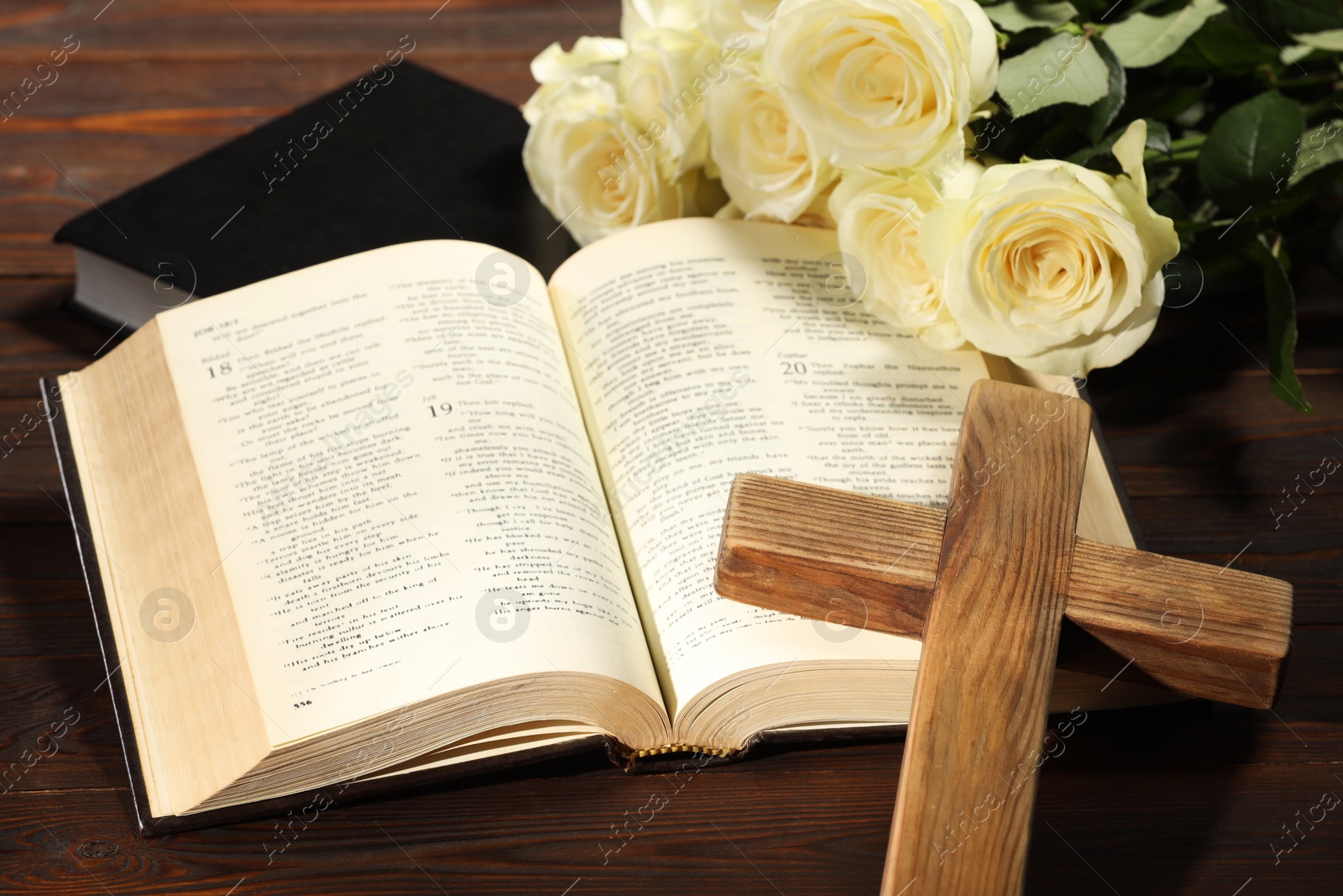 Photo of Bibles, cross and roses on wooden table, closeup. Religion of Christianity