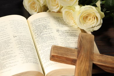 Photo of Bible, cross and roses on table, closeup. Religion of Christianity