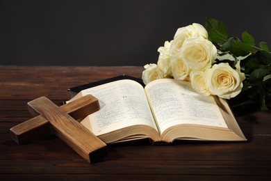 Bibles, cross and roses on wooden table against gray background. Religion of Christianity