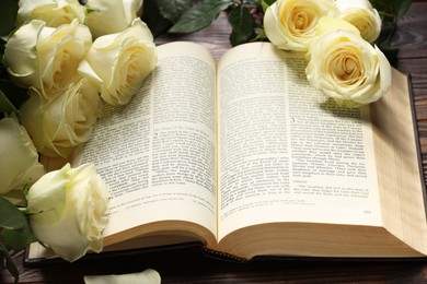 Photo of Bible and roses on table, closeup. Religion of Christianity