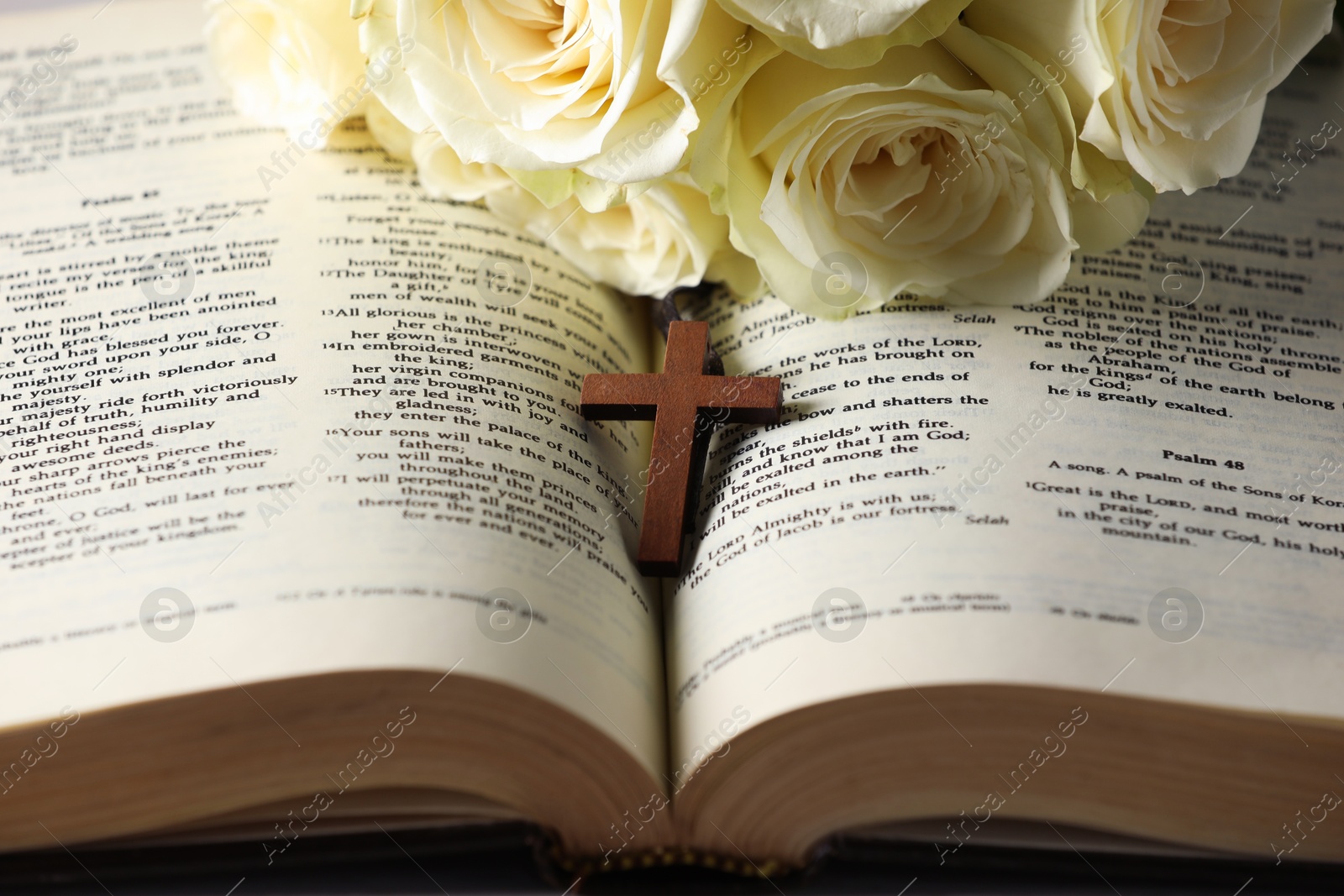 Photo of Bible, cross and roses on table, closeup. Religion of Christianity