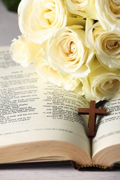 Photo of Bible, cross and roses on light table, closeup. Religion of Christianity