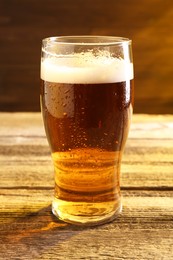 Glass of beer with froth on wooden table