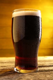 Glass of beer with froth on wooden table