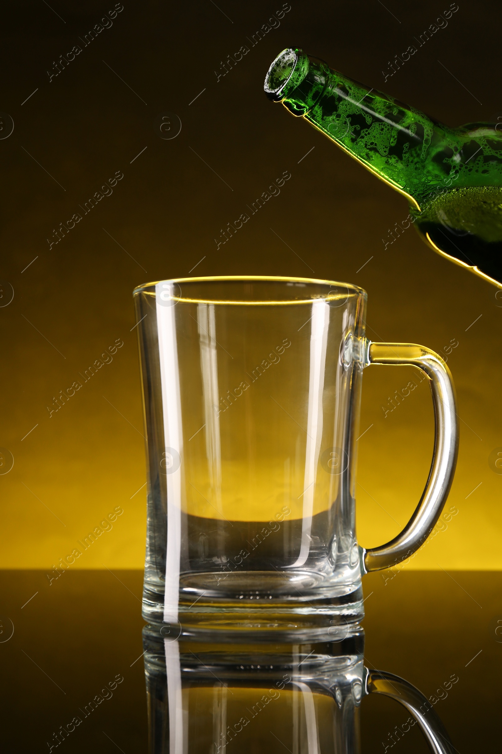 Photo of Pouring beer into glass mug from bottle on dark table, closeup