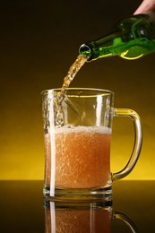 Photo of Man pouring beer into glass mug from bottle on dark table, closeup