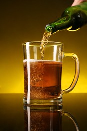 Photo of Man pouring beer into glass mug from bottle on dark table, closeup