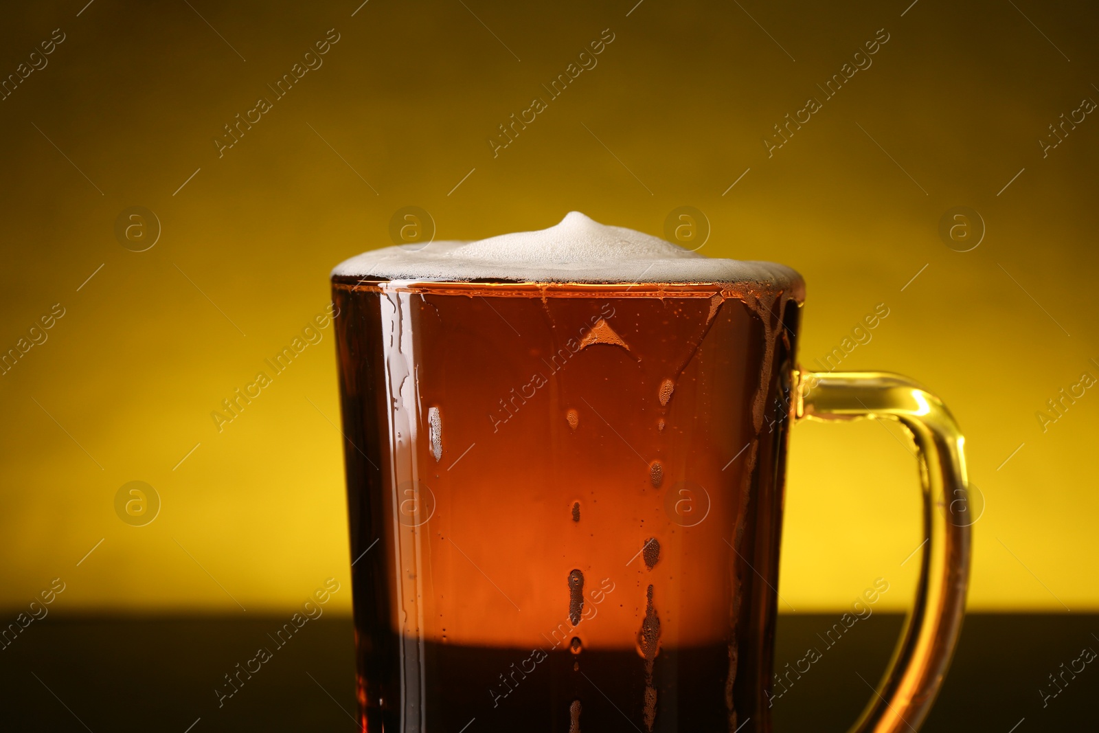 Photo of Glass of beer with froth on dark table, closeup