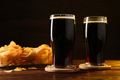 Glasses of beer and potato chips on wooden table